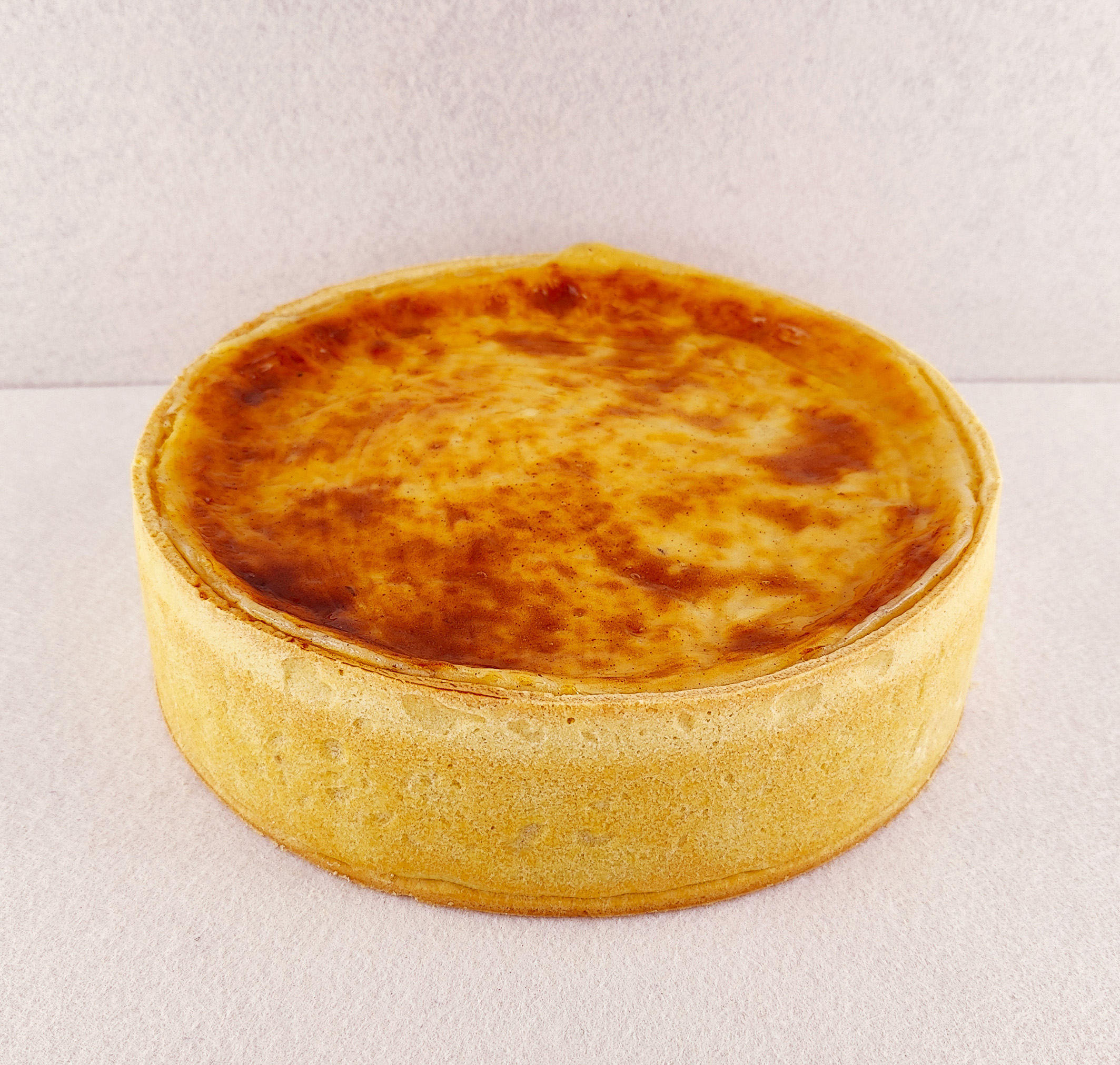 Flan parisino a la vainilla fotografiado en ángulo de 45 grados, con masa brisa ligeramente tostada envolviendo la base y los laterales, y superficie dorada.