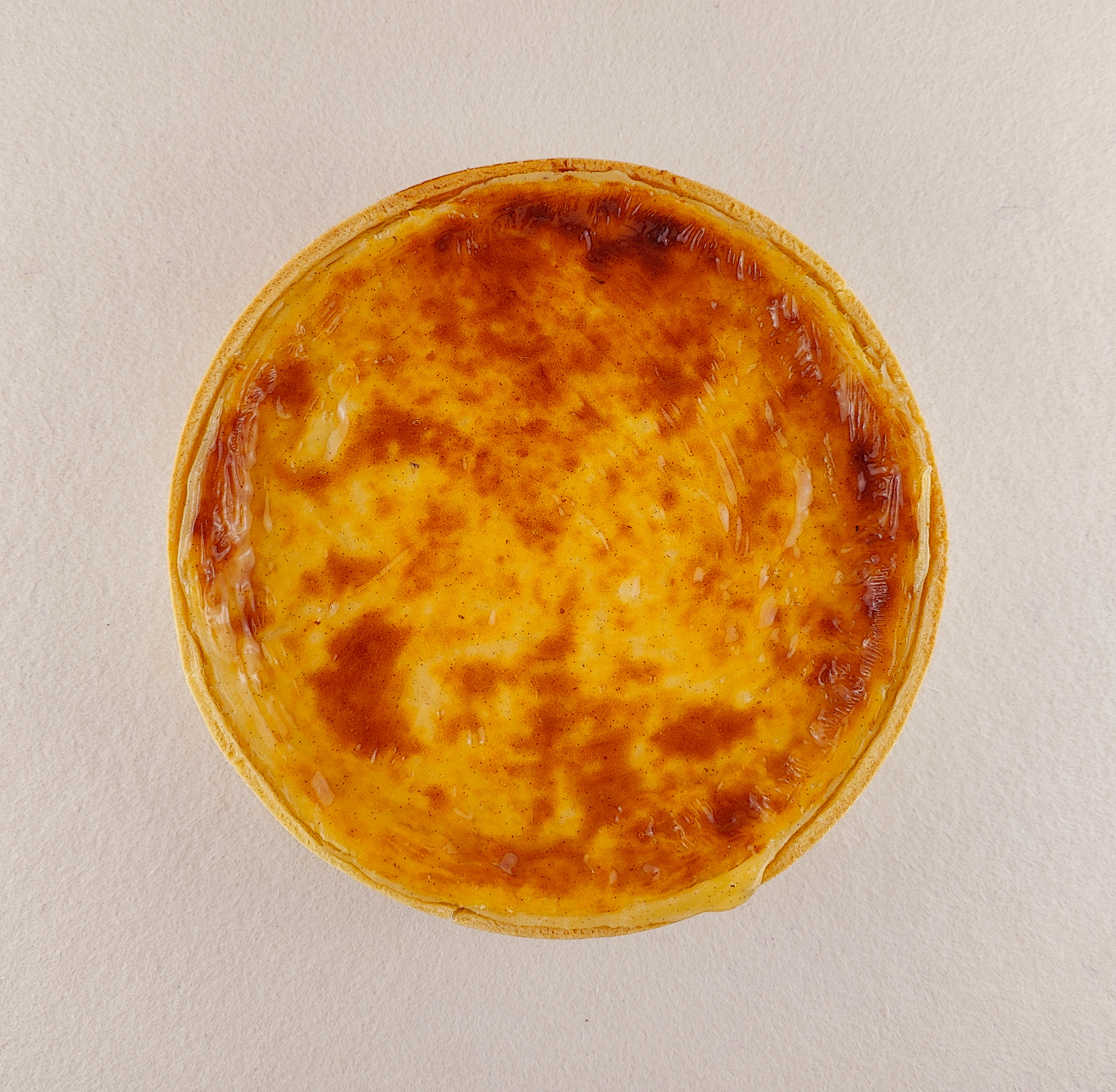 Flan parisino a la vainilla visto desde arriba, con superficie tostada y masa brisa alrededor.