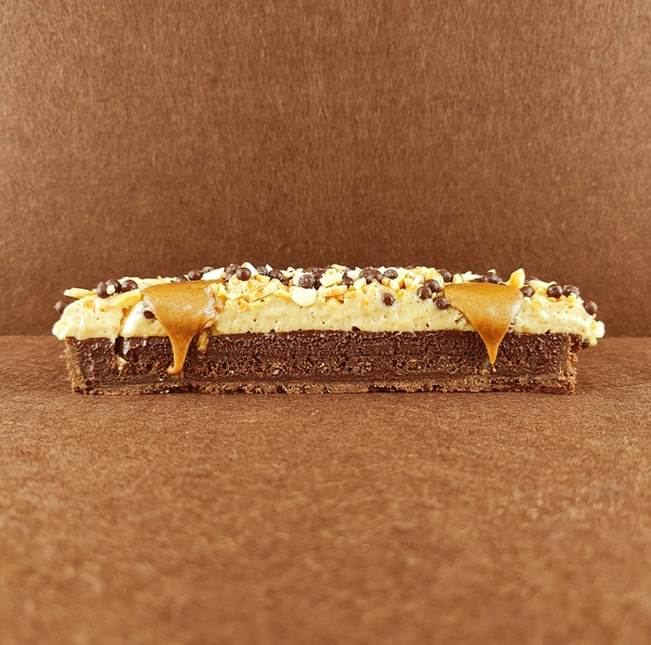 Primer plano de una Tarta Ópera cuadrada, resaltando la textura del glaseado chocolate, la suavidad de la crema de café, la cremosidad de la ganaché de chocolate y la esponjosidad del bizcocho gioconda empapado en café.