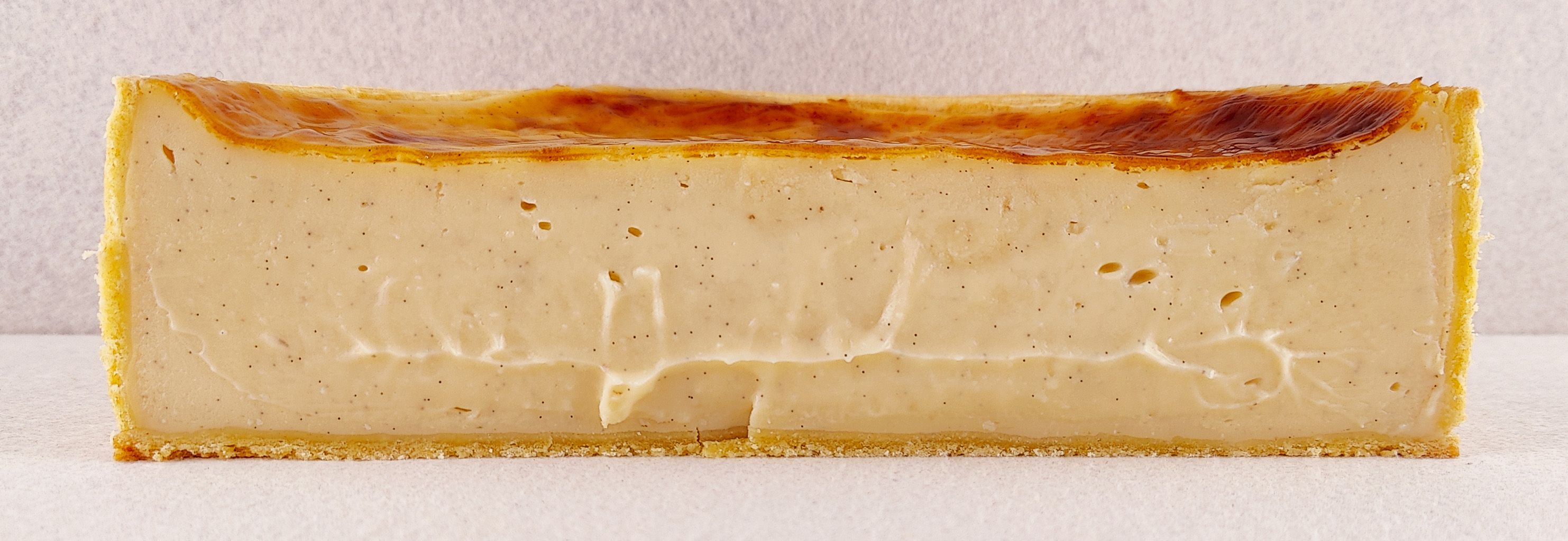 Flan parisino a la vainilla cortado de lado a lado, mostrando el interior cremoso de vainilla y la masa brisa de la base y los laterales.