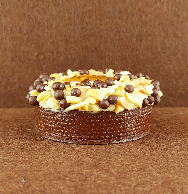 Primer plano de una porción rectangular de Tarta Ópera, destacando la textura lisa del glaseado de chocolate y la definición de las capas de bizcocho de almendra, crema de café y ganache de chocolate.