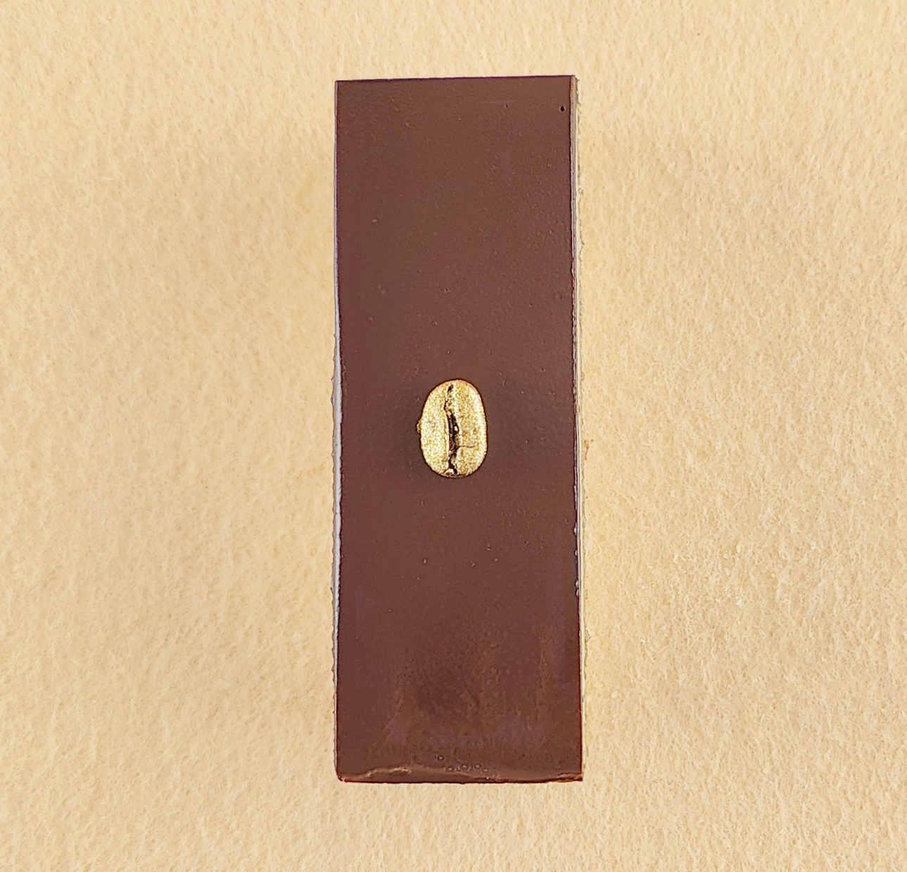 Porción individual rectangular de Tarta Ópera vista de frente, con sus capas alternas de bizcocho de almendra, crema de café y ganache de chocolate perfectamente alineadas.